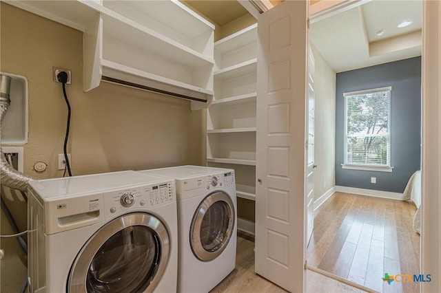 washroom with laundry area, independent washer and dryer, baseboards, and light wood-style floors