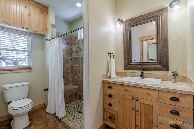 full bath with vanity, toilet, baseboards, and tiled shower