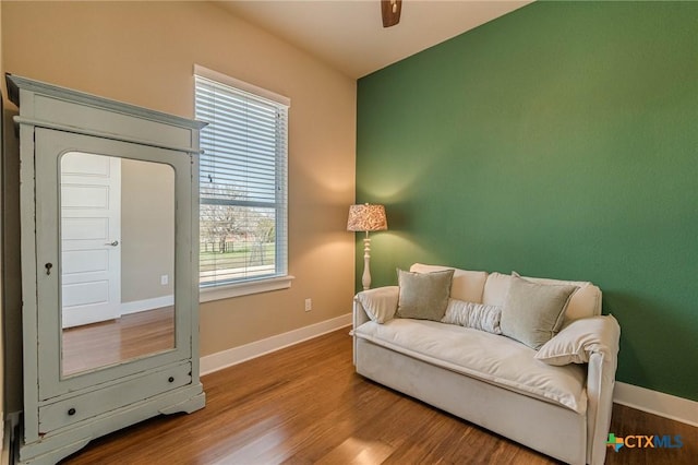 sitting room with a ceiling fan, wood finished floors, and baseboards