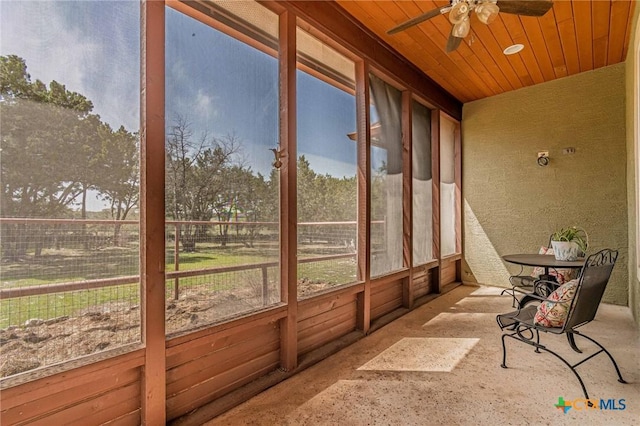 unfurnished sunroom with a ceiling fan, plenty of natural light, and wood ceiling