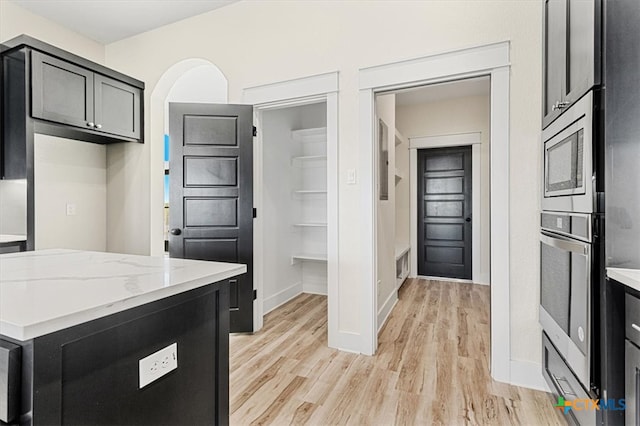 kitchen featuring light stone countertops, appliances with stainless steel finishes, and light wood-type flooring