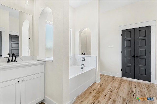 bathroom with a tub to relax in, vanity, and hardwood / wood-style flooring