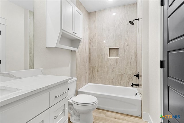 full bathroom featuring vanity, wood-type flooring, tiled shower / bath, and toilet