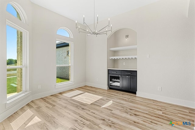 unfurnished dining area with light wood-type flooring and an inviting chandelier