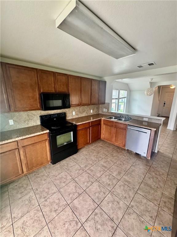 kitchen featuring visible vents, a sink, a peninsula, brown cabinets, and black appliances