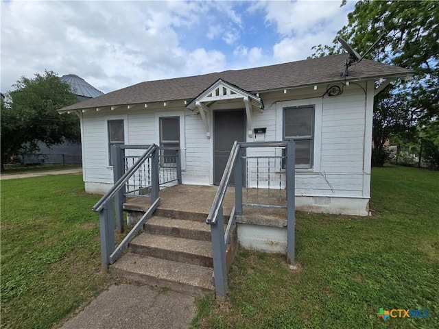 bungalow-style house featuring crawl space, roof with shingles, and a front yard