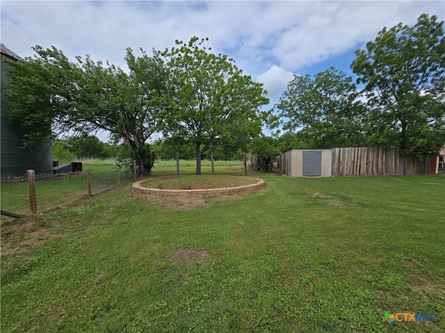 view of yard featuring a storage unit, an outdoor structure, and fence