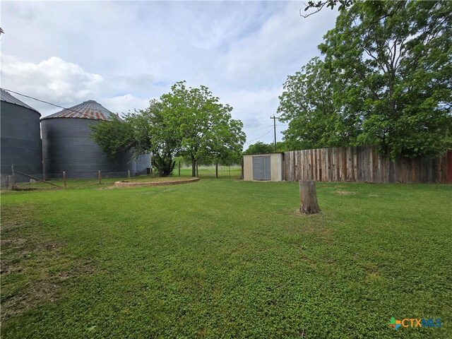 view of yard with an outdoor structure, fence, and a shed