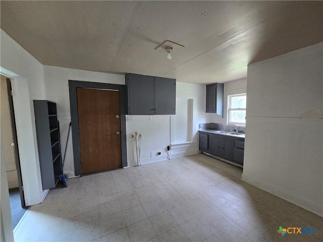 interior space featuring baseboards, a sink, and light floors