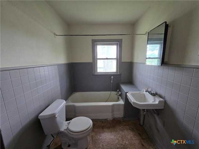 bathroom with toilet, tile walls, a sink, and a bath