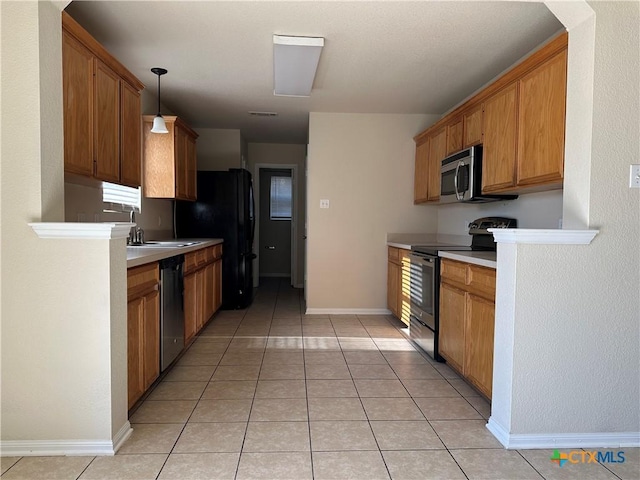 kitchen featuring sink, light tile patterned flooring, hanging light fixtures, and appliances with stainless steel finishes