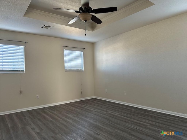 empty room featuring a raised ceiling, crown molding, ceiling fan, and dark wood-type flooring