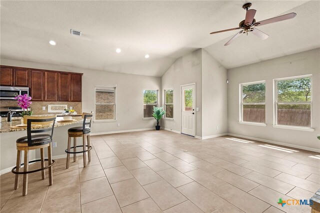 668 Peacock Ln, New Braunfels, TX 78310 - kitchen featuring stove, light stone countertops, stainless steel microwave, open floor plan, and light tile patterned flooring