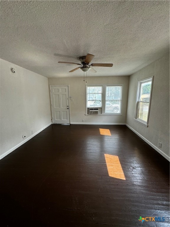 spare room featuring a wealth of natural light, a textured ceiling, ceiling fan, and dark hardwood / wood-style flooring