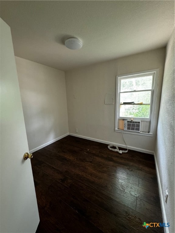 empty room with dark wood-type flooring, cooling unit, and a textured ceiling