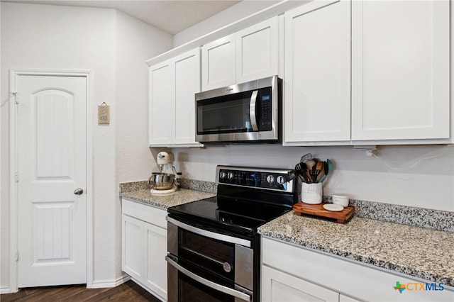 1004 Norway Dr, Seguin, TX 78155 - kitchen featuring appliances with stainless steel finishes, white cabinetry, light stone counters, and dark wood-type flooring