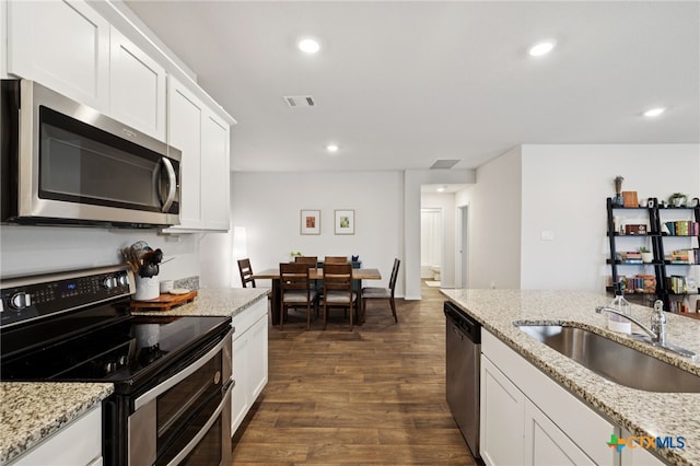 1004 Norway Dr, Seguin, TX 78155 - kitchen with stainless steel appliances, recessed lighting, white cabinets, dark wood-style flooring, and light stone countertops