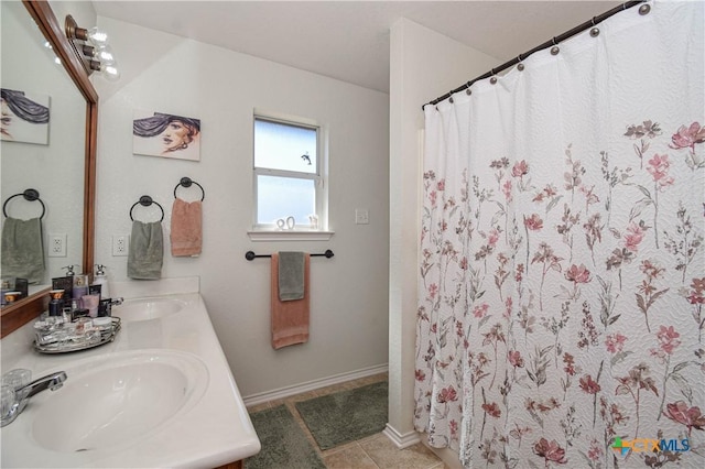 bathroom featuring tile patterned flooring, double vanity, baseboards, and a sink