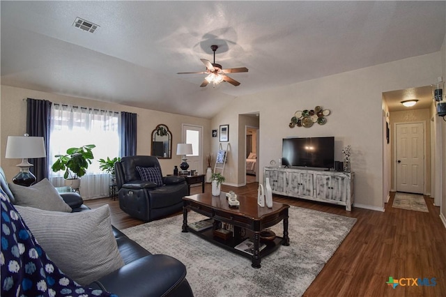 living area with wood finished floors, baseboards, a ceiling fan, visible vents, and vaulted ceiling