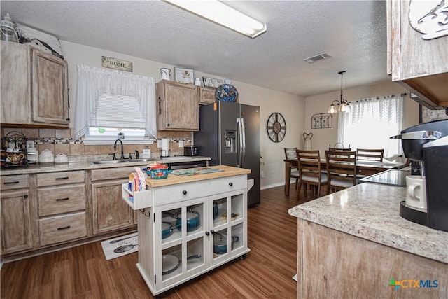 kitchen featuring visible vents, stainless steel refrigerator with ice dispenser, a sink, light countertops, and dark wood-style flooring