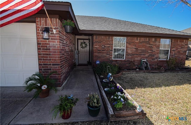 property entrance featuring brick siding, a yard, a garage, and roof with shingles