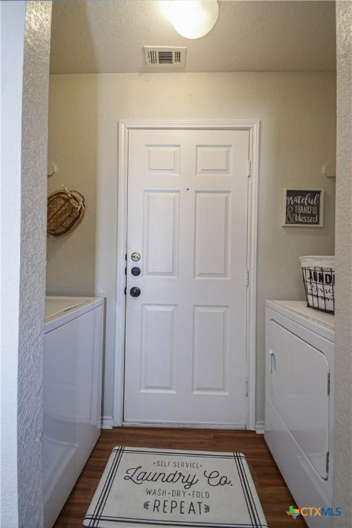 laundry room with washer and dryer, laundry area, dark wood finished floors, and visible vents