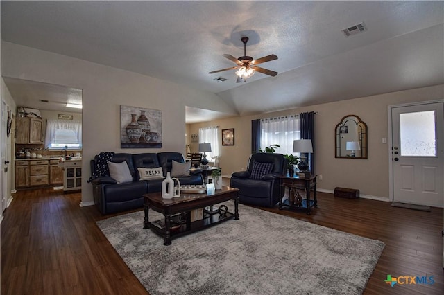 living area featuring vaulted ceiling, dark wood-style floors, a ceiling fan, and visible vents