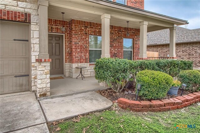 doorway to property with brick siding, a porch, and stone siding