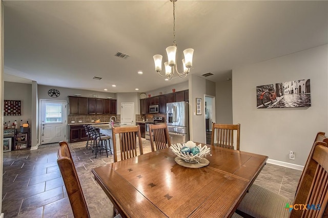 dining area featuring recessed lighting, visible vents, stone finish flooring, baseboards, and a chandelier