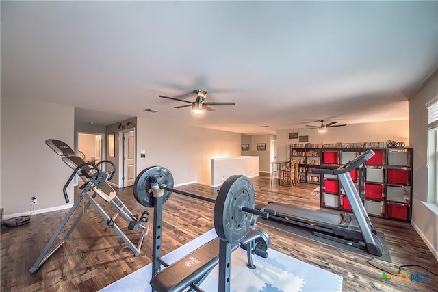 exercise area with wood finished floors, visible vents, a ceiling fan, and baseboards