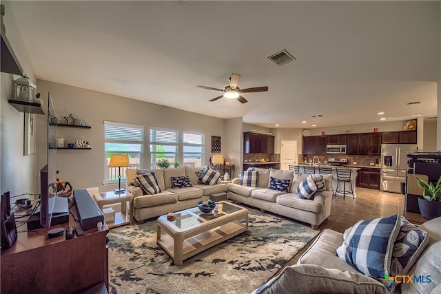 living area featuring tile patterned floors, visible vents, and ceiling fan