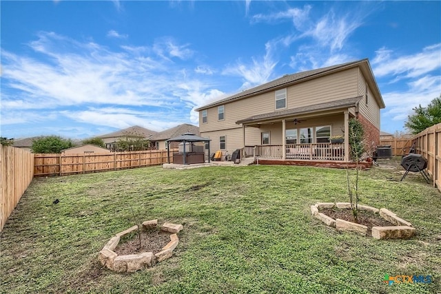 rear view of property with a fenced backyard, a gazebo, a yard, and ceiling fan