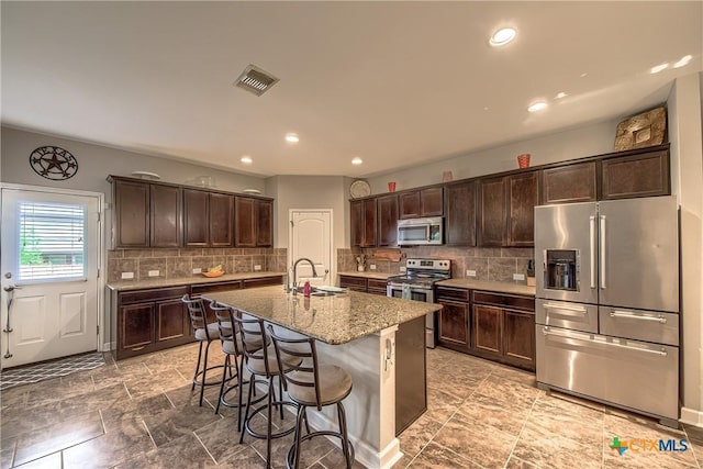 kitchen featuring visible vents, dark brown cabinetry, stainless steel appliances, and a sink