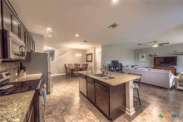 kitchen with a sink, open floor plan, a kitchen bar, appliances with stainless steel finishes, and visible vents