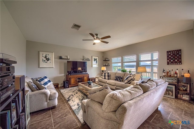 living area with a ceiling fan, visible vents, and a bar