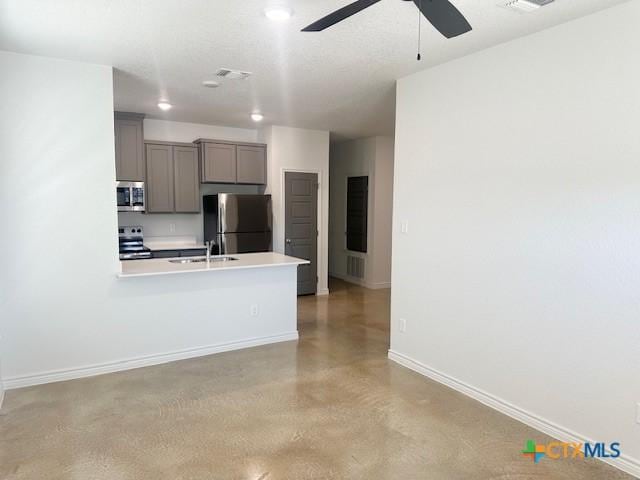 kitchen featuring gray cabinetry, a sink, baseboards, light countertops, and appliances with stainless steel finishes