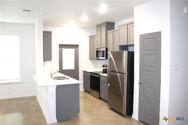 kitchen with gray cabinetry, sink, stainless steel appliances, and kitchen peninsula