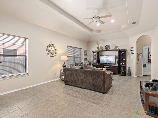 9823 Amberg Path, Helotes, TX 78023 - living room with arched walkways, a ceiling fan, and a tray ceiling