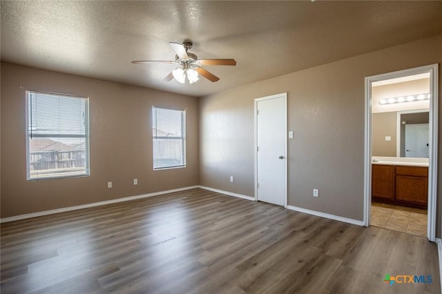 unfurnished bedroom featuring multiple windows, ceiling fan, and hardwood / wood-style flooring