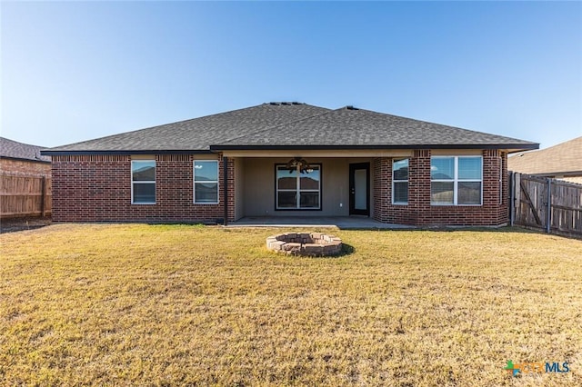 rear view of house with a lawn, a patio, and an outdoor fire pit