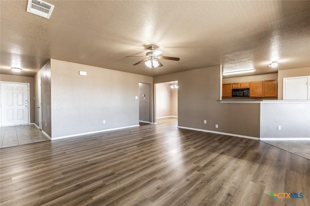 unfurnished living room with dark hardwood / wood-style floors, ceiling fan, and a textured ceiling