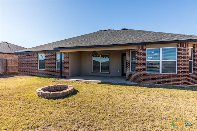 rear view of property featuring a lawn, a patio, and an outdoor fire pit