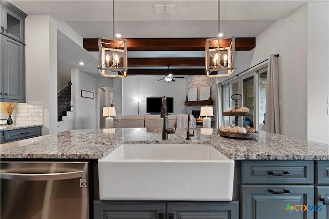 kitchen featuring sink, dishwasher, decorative backsplash, a stone fireplace, and beamed ceiling