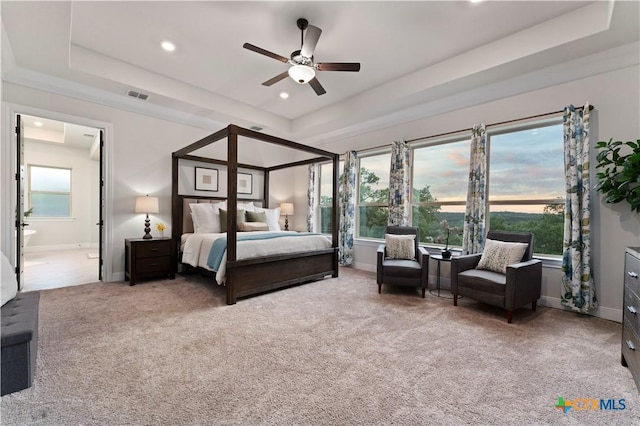 bedroom with ceiling fan, connected bathroom, a raised ceiling, and carpet