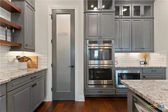 kitchen featuring light stone countertops, appliances with stainless steel finishes, gray cabinetry, and decorative backsplash