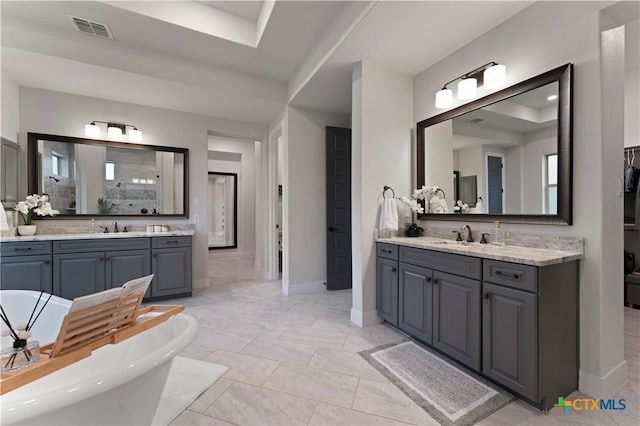 bathroom featuring vanity, tile patterned flooring, a tray ceiling, and a bathing tub