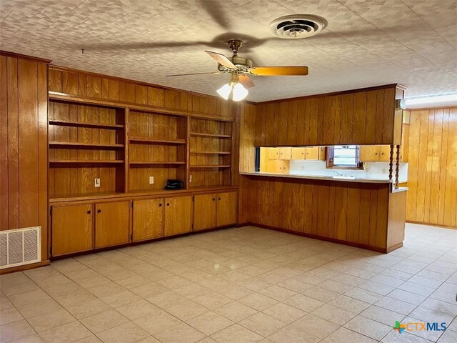 6414 Fm 234 N, Edna, TX 77957 - kitchen featuring wooden walls, brown cabinetry, a ceiling fan, crown molding, and baseboards