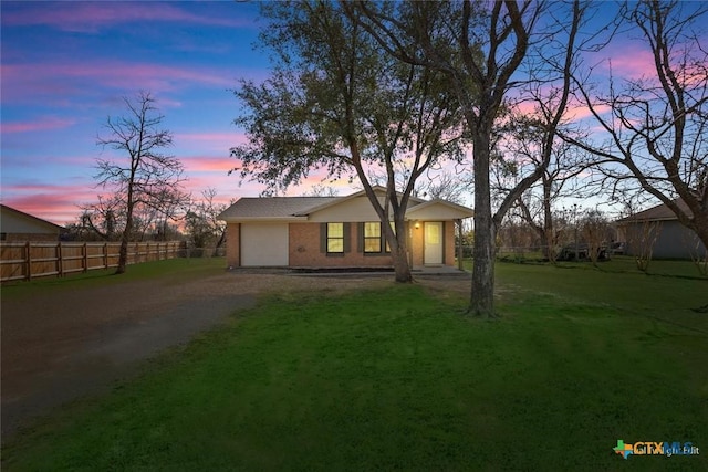 view of front of property with an attached garage, fence, a lawn, and dirt driveway