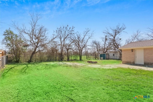view of yard with an outdoor fire pit, a fenced backyard, and an outdoor structure