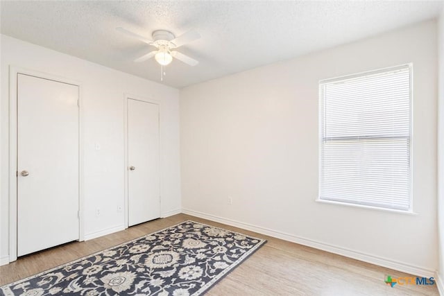 bedroom with baseboards, a textured ceiling, wood finished floors, and a ceiling fan